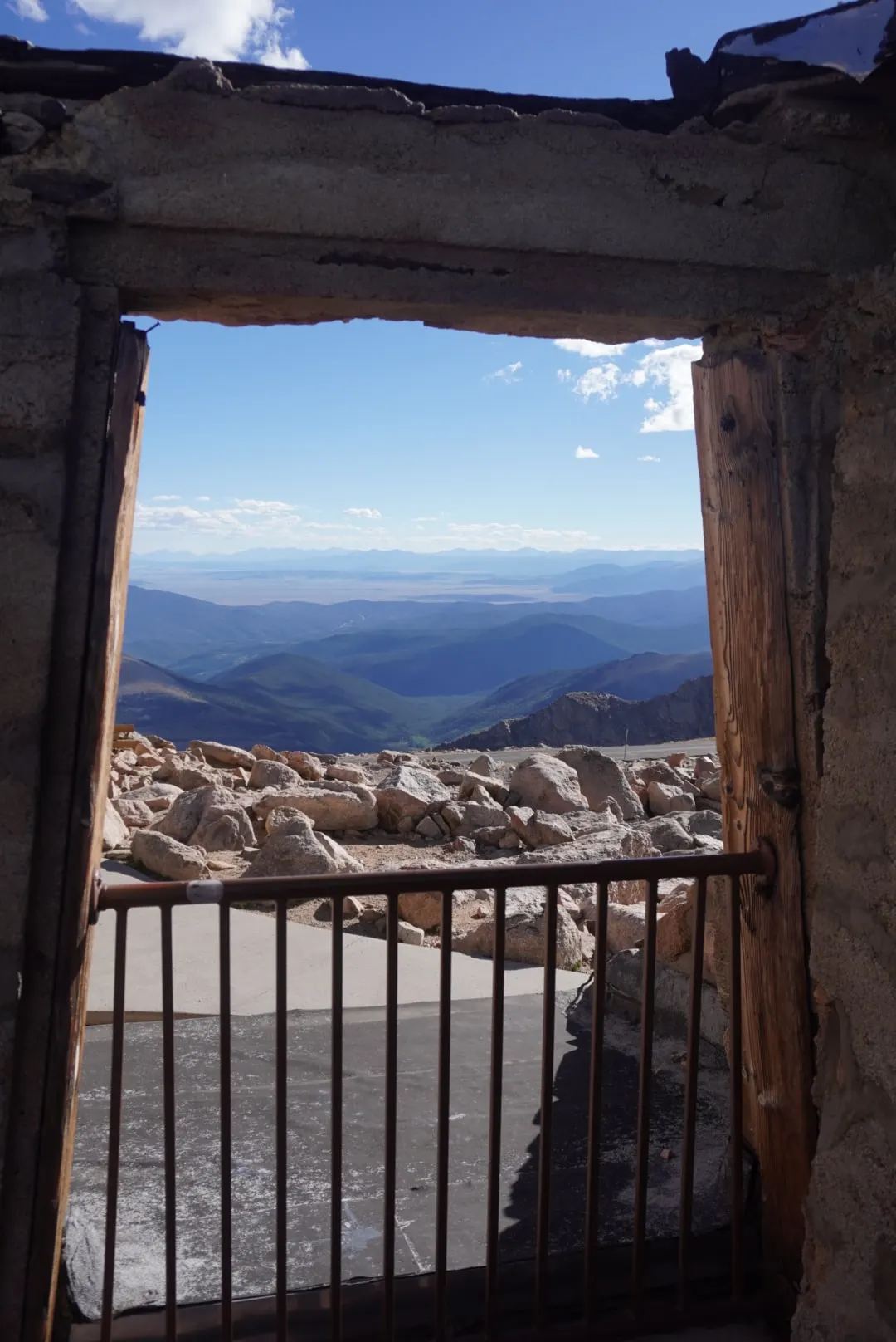 Mountain ranges seen through the frame of an old ruined doorway with an iron railing.